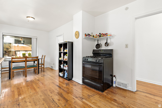 372 800 East Provo, UT 84606 - Photo 8 of 29 Hardwood flooring throughout a dining area with a large window and a kitchen area featuring a black gas range