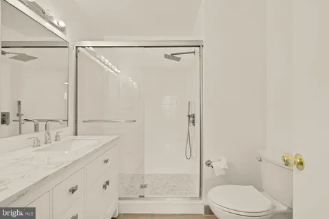 a bathroom with a granite countertop sink mirror and a shower
