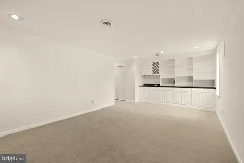 a view of kitchen with refrigerator and white cabinets