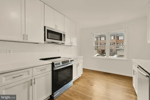 a kitchen with granite countertop cabinets stainless steel appliances and wooden floor