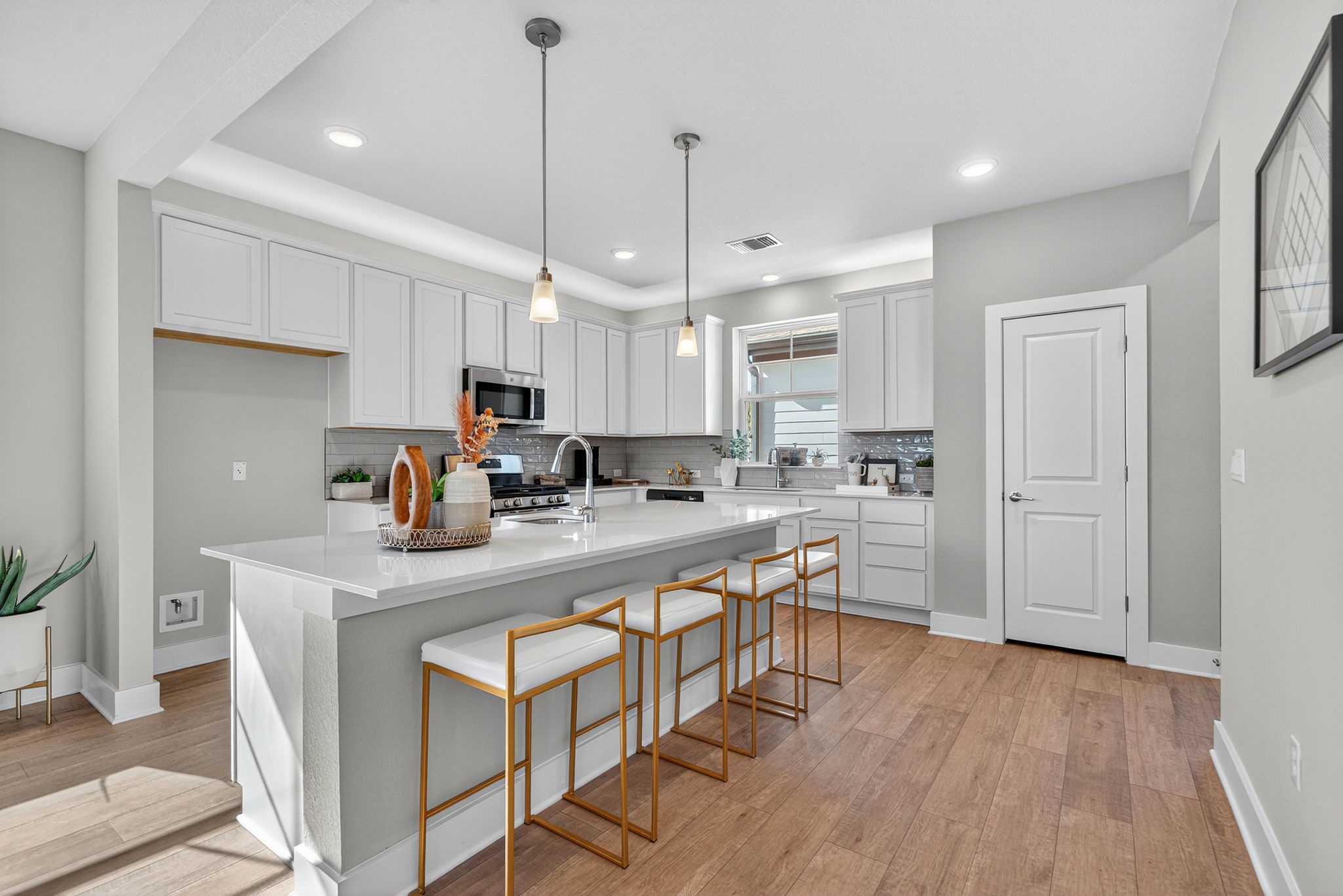5902 Rotunda View Austin, TX 78747 - Photo 6 of 38 Kitchen with a breakfast bar, white cabinets, decorative light fixtures, backsplash, and a kitchen island with sink