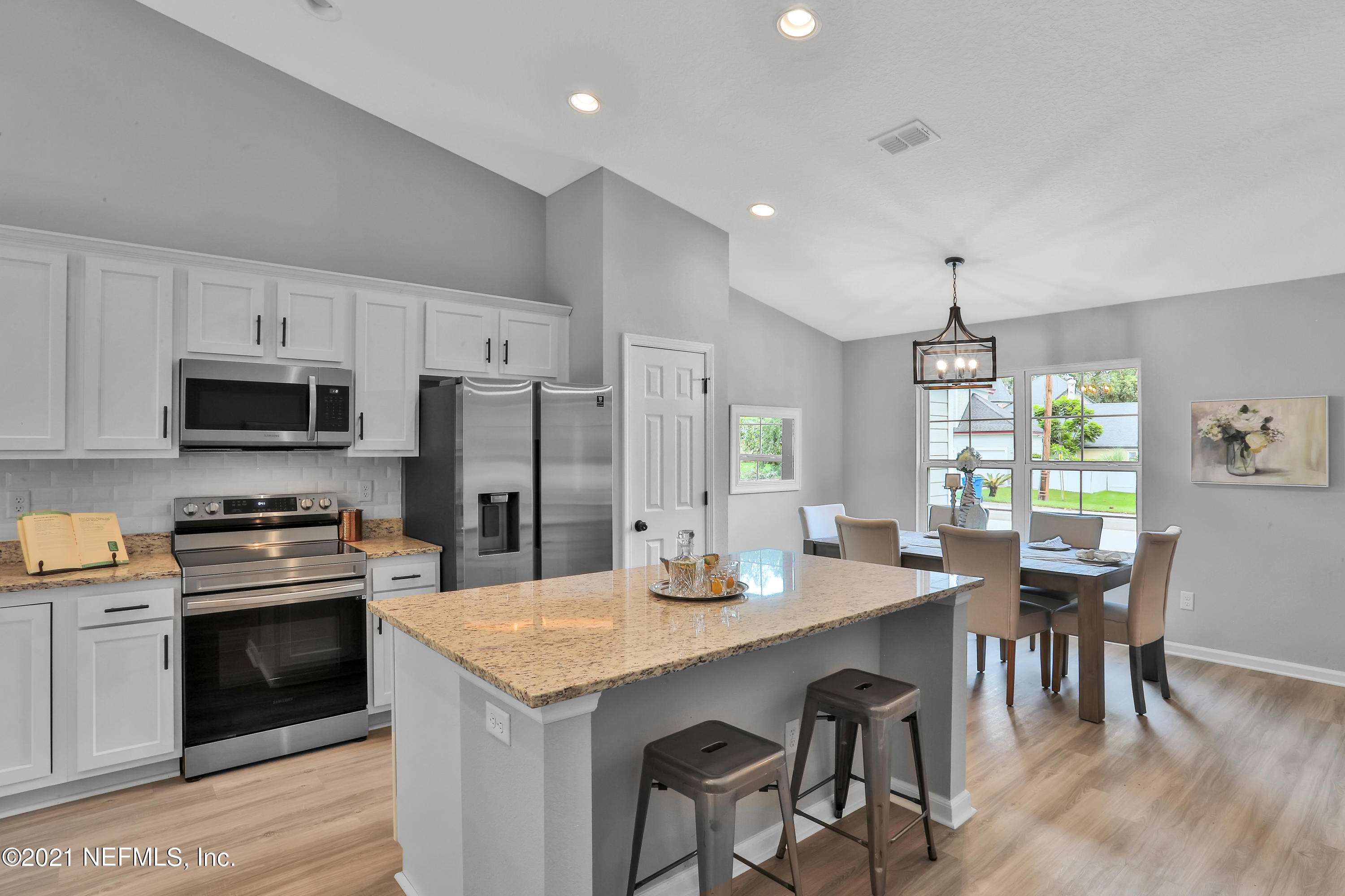 6442 Heidi Road Jacksonville, FL 32277 - Photo 6 of 30 a kitchen with stainless steel appliances kitchen island granite countertop a dining table and chairs a refrigerator with wooden floors