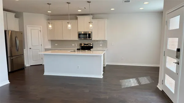 a kitchen with stainless steel appliances granite countertop a sink a stove a refrigerator and a oven with wooden floor