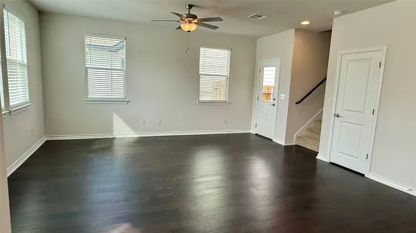 an empty room with wooden floor and windows