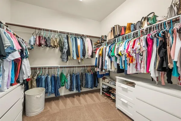 a view of walk in closet with clothes and shoes