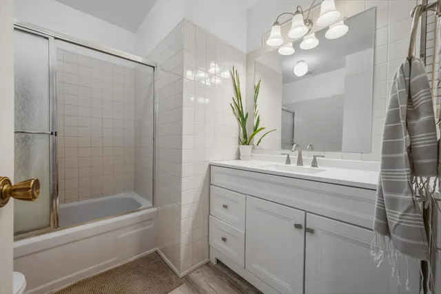 a bathroom with a bathtub shower sink vanity and mirror