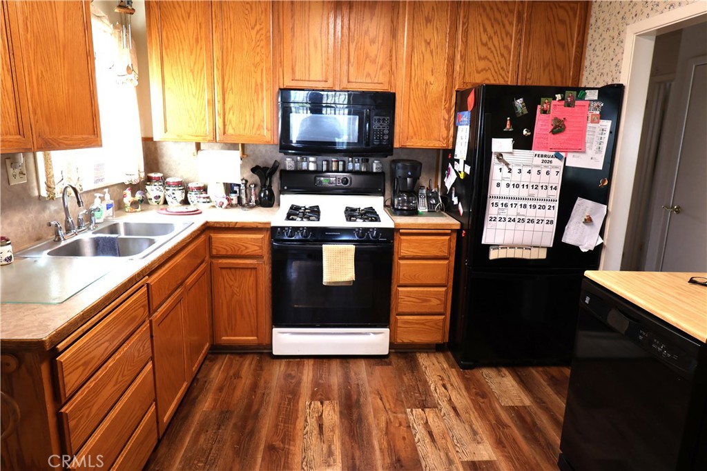 1409 North Street Corning, CA 96021 - Photo 21 of 40 a kitchen with stainless steel appliances a stove top oven a sink dishwasher and a microwave with wooden floor