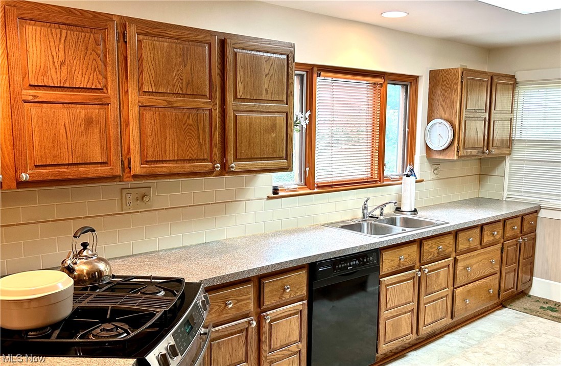 2920 Kent Road Silver Lake, OH 44224 - Photo 6 of 28 Kitchen with range with two ovens, black dishwasher, tile flooring, brown cabinets, light countertops, and backsplash