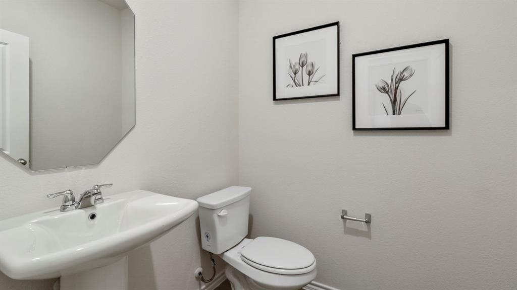 636 Dunham Road Nevada, TX 75173 - Photo 28 of 31 Pedestal sink with chrome faucet, an octagonal wall-mounted mirror, and a white toilet