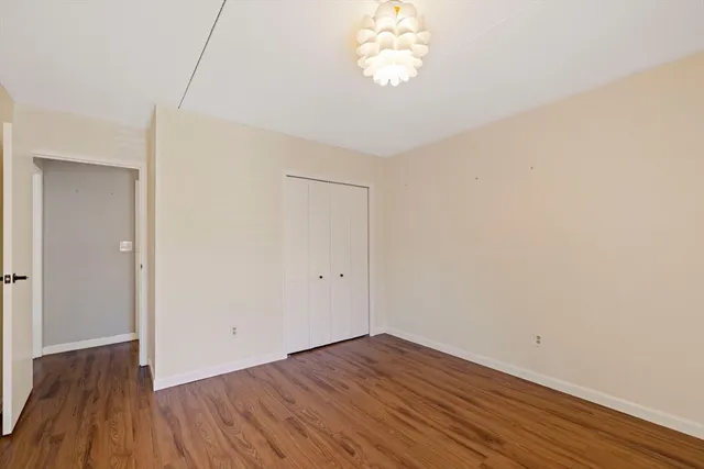 a view of a room with wooden floor and a chandelier fan