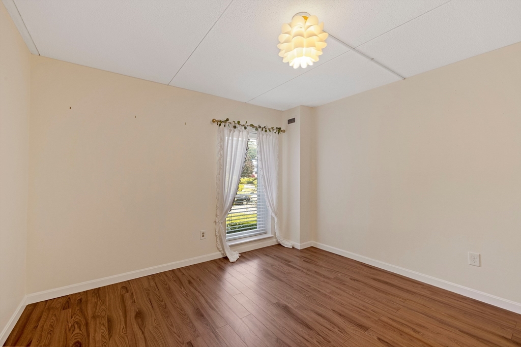 50-56 Broadlawn Park, Unit 221 Boston, MA 02467 - Photo 13 of 29 an empty room with wooden floor and a window