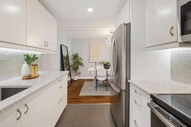 a kitchen with stainless steel appliances white cabinets and wooden floor