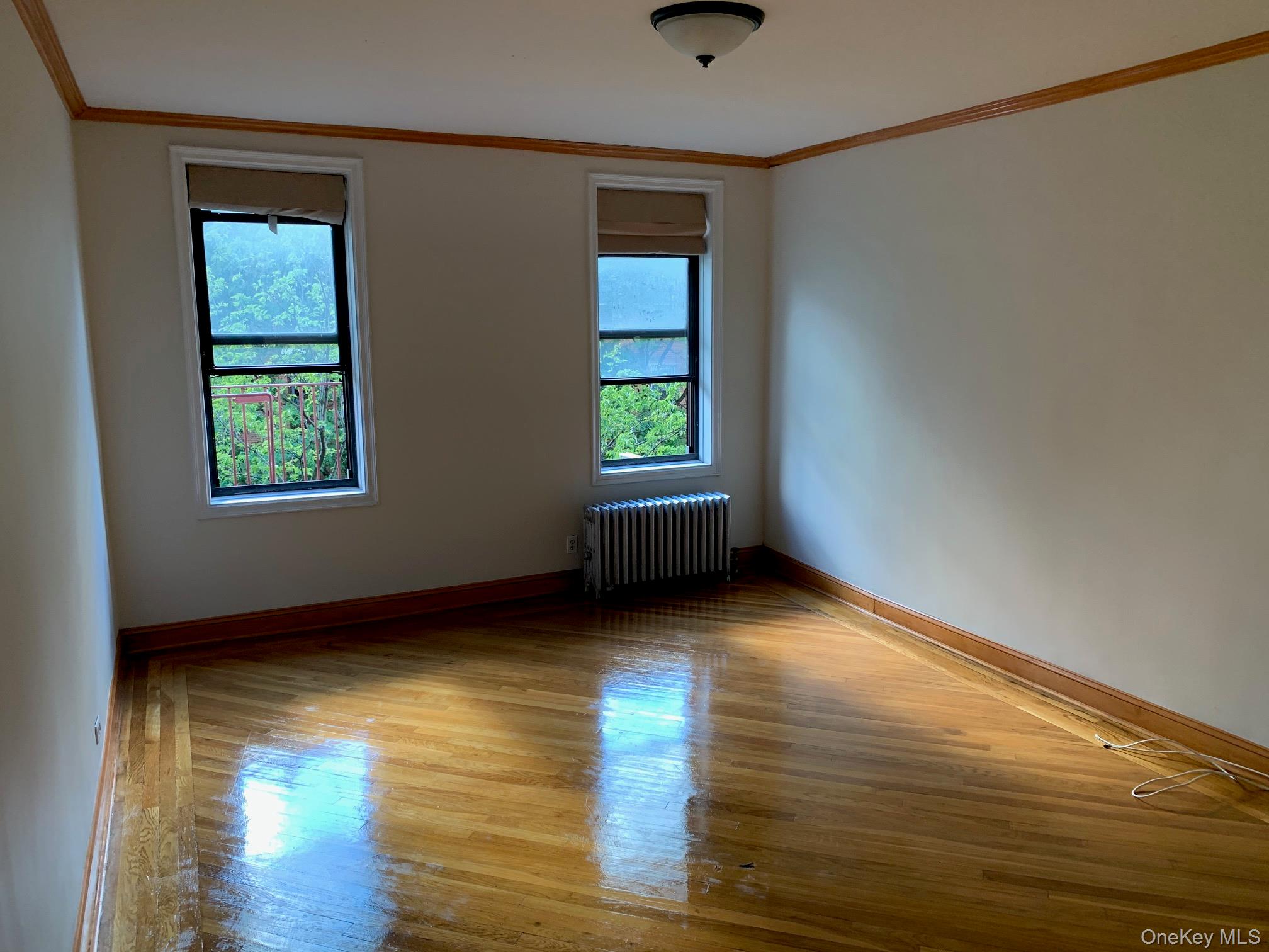 43-33 48th Street, Unit 3C Queens, NY 11104 - Photo 12 of 15 an empty room with wooden floor and windows