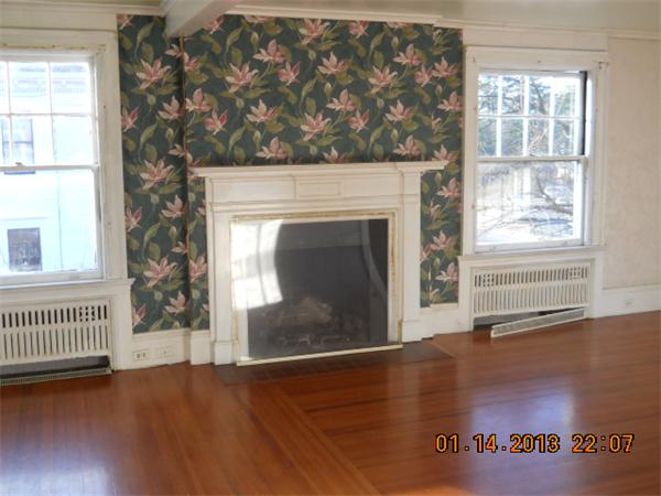 321 Longhill Street Springfield, MA 01108 - Photo 5 of 5 an empty room with wooden floor a fireplace and windows