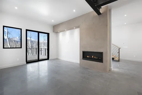 an empty room with windows and fireplace