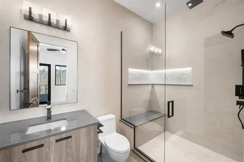 a bathroom with a granite countertop sink mirror vanity and toilet