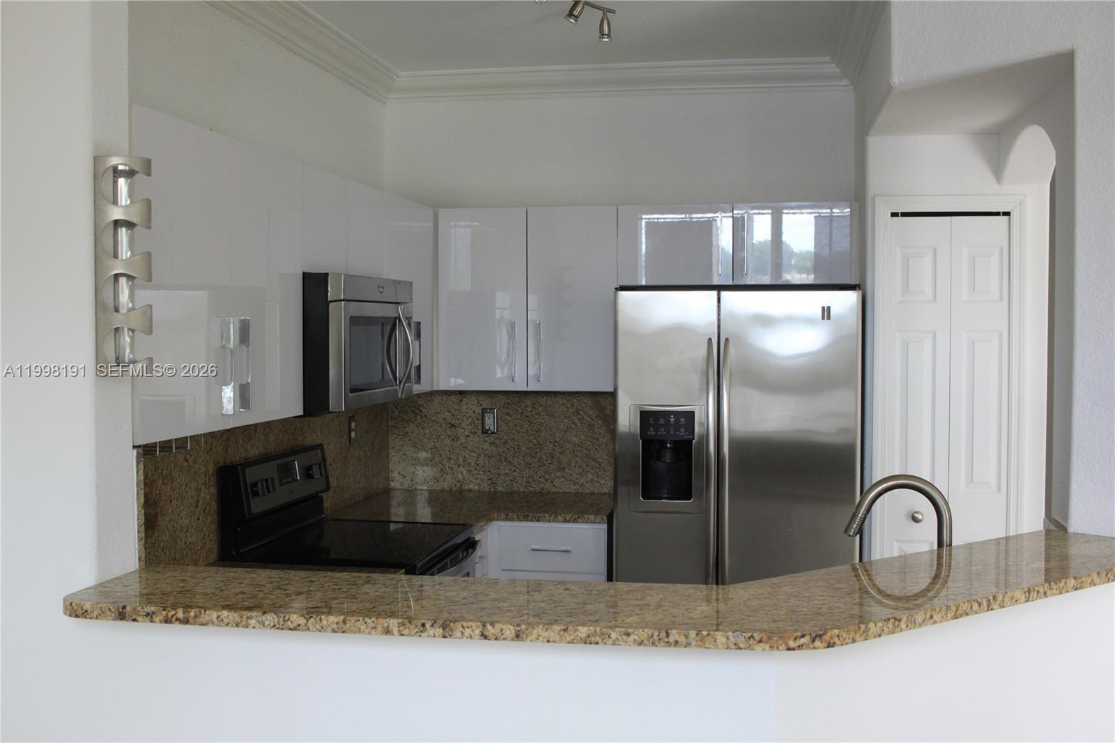 11675 Northwest 78th Lane Doral, FL 33178 - Photo 2 of 12 a kitchen with kitchen island a counter top space a refrigerator and cabinets