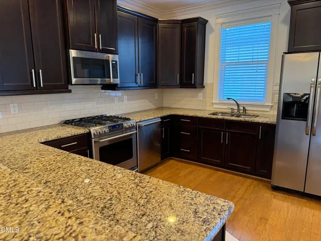 a kitchen with stainless steel appliances granite countertop a stove a sink and a microwave