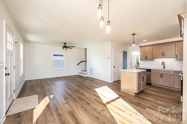 a view of a kitchen with kitchen island a sink wooden floor and a counter top space