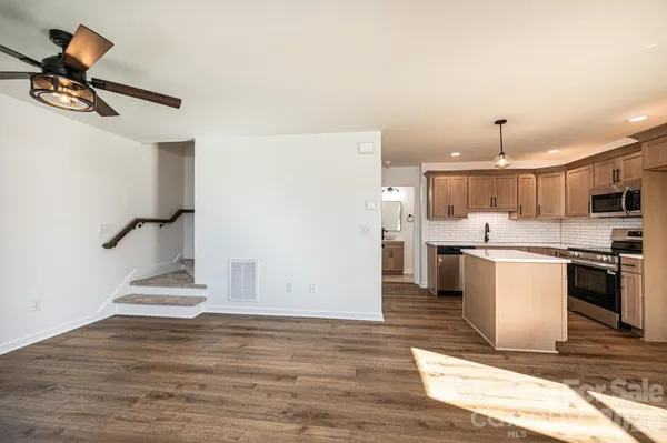 a living room with stainless steel appliances kitchen island a stove a refrigerator and a view of living room