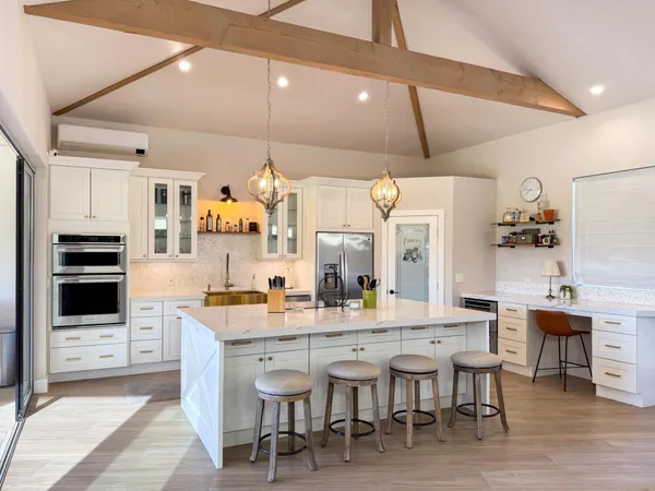 a dining hall with stainless steel appliances kitchen island granite countertop a table chairs and a refrigerator