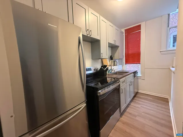 a kitchen with stainless steel appliances a refrigerator sink and wooden floor