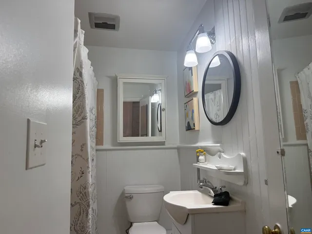 a bathroom with a toilet a sink and mirror