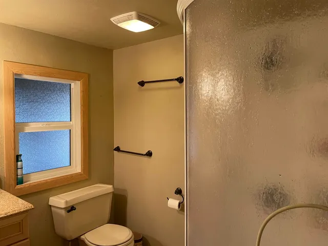 a bathroom with a granite countertop toilet and a shower