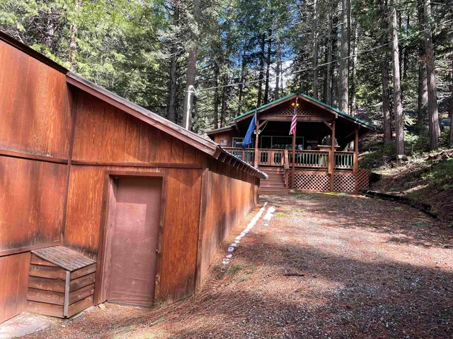 a backyard of a house with wooden fence and large trees