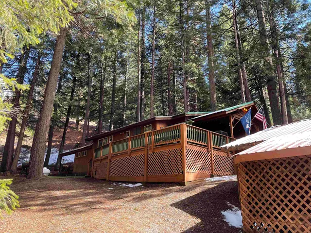 a view of a house with a large tree and wooden fence