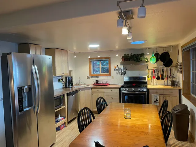 a kitchen with kitchen island a counter top space a sink a refrigerator and a stove top oven