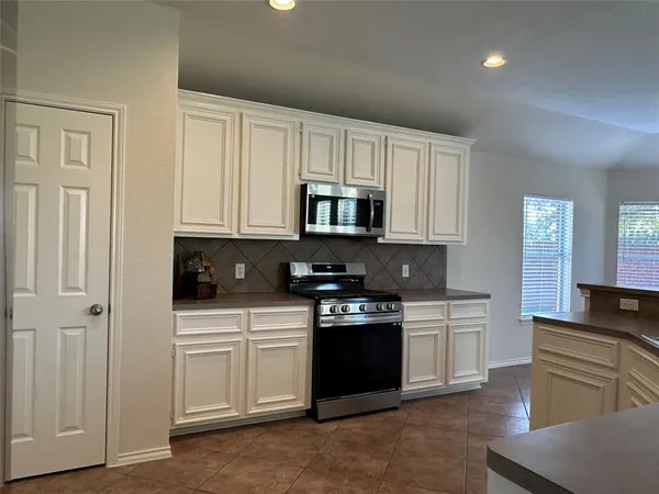 a kitchen with white cabinets and appliances