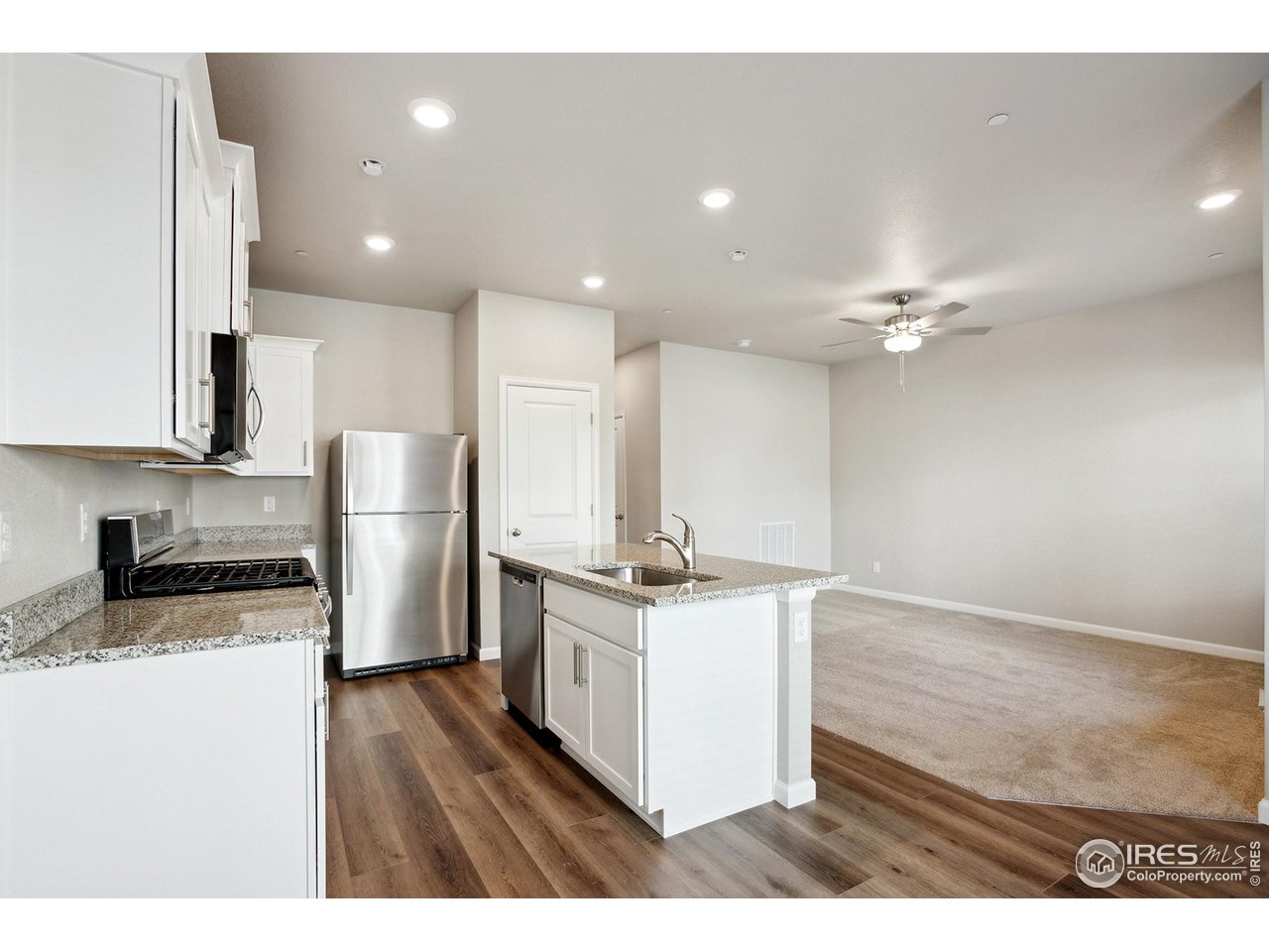 199 Robin Road Johnstown, CO 80534 - Photo 7 of 30 a kitchen with stainless steel appliances granite countertop a stove a refrigerator a sink and white cabinets with wooden floor