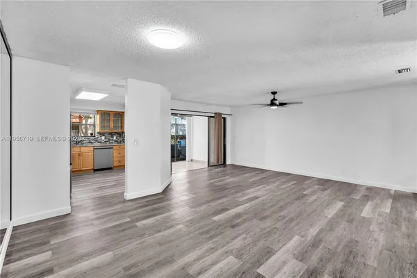 a view of a big room with wooden floor and a kitchen