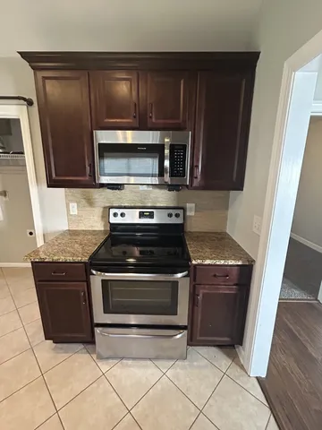 a kitchen with granite countertop a stove microwave and cabinets