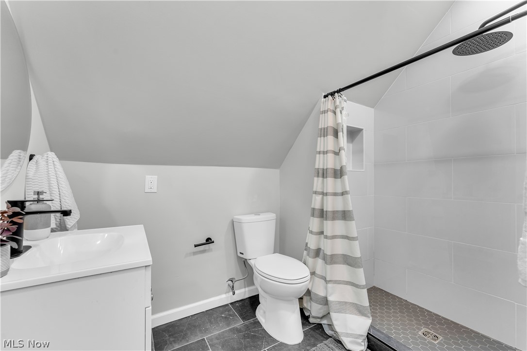 1000 Pennfield Road Cleveland, OH 44121 - Photo 28 of 34 Bathroom with tile flooring, vaulted ceiling, vanity, a shower with curtain, and toilet