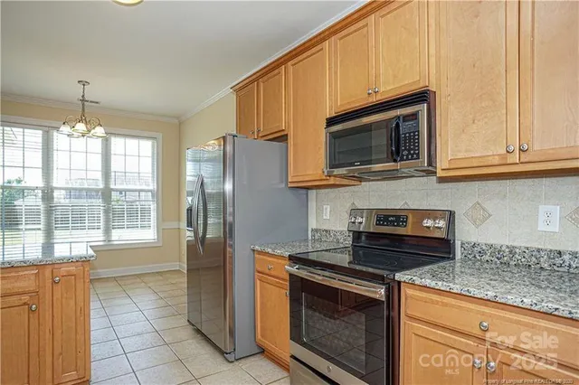 a kitchen with granite countertop a refrigerator stove and microwave