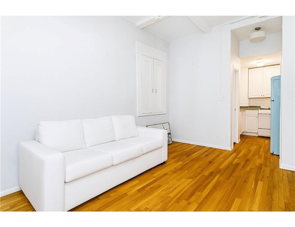 41 Jane Street, Unit 5B Manhattan, NY 10014 - Photo 5 of 8 a living room with a bed furniture and a wooden floor