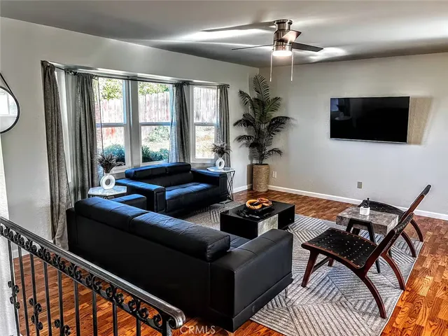 a living room with furniture a flat screen tv and a floor to ceiling window