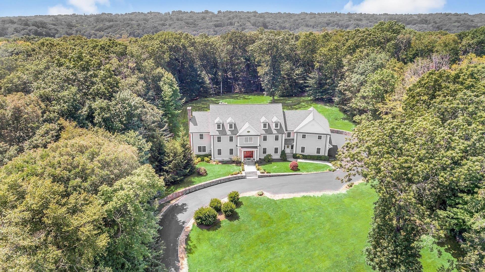 an aerial view of residential house with outdoor space and trees all around
