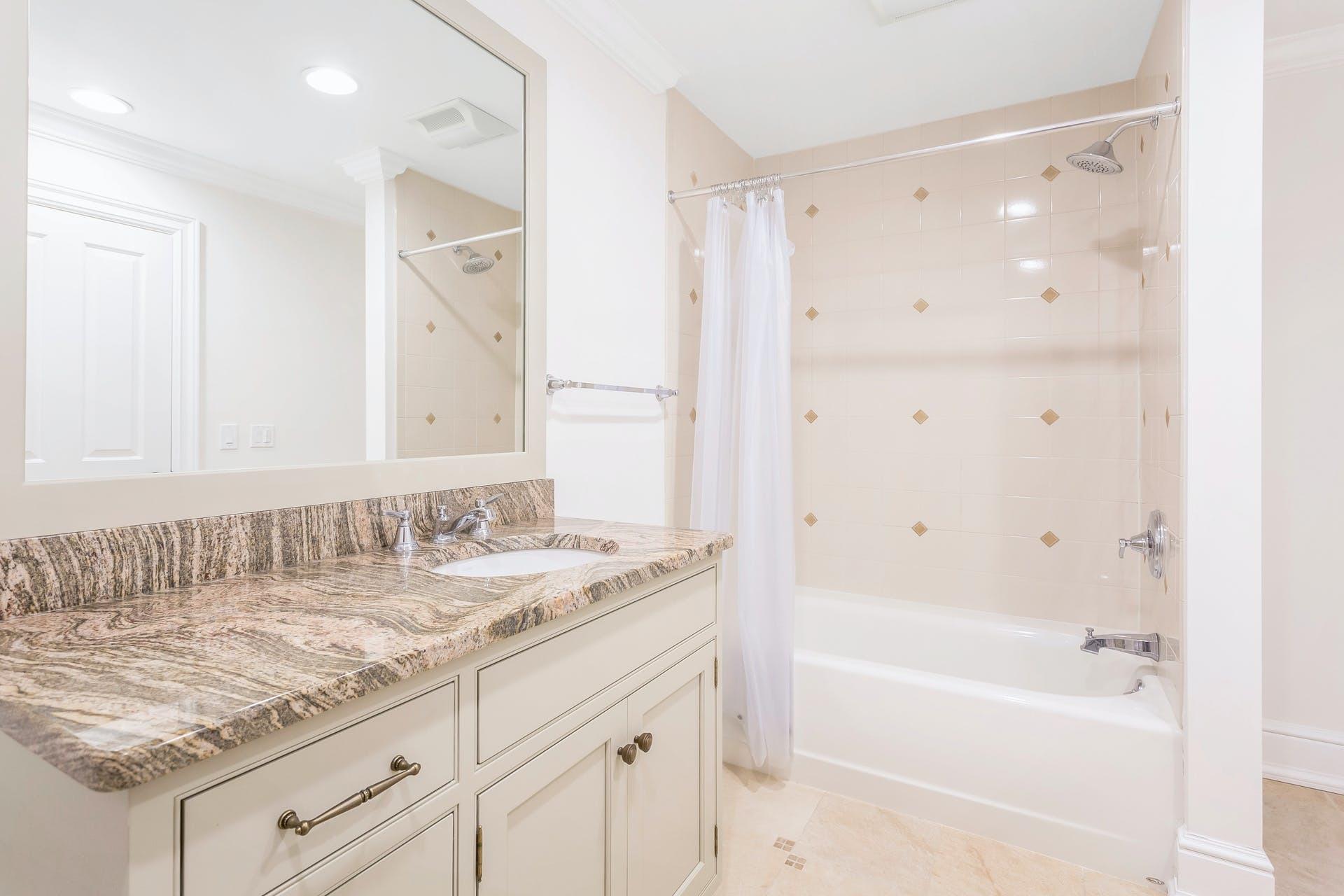 274 Mariomi Road New Canaan, CT 06840 - Photo 40 of 56 a bathroom with a granite countertop sink a mirror a shower and a bathtub