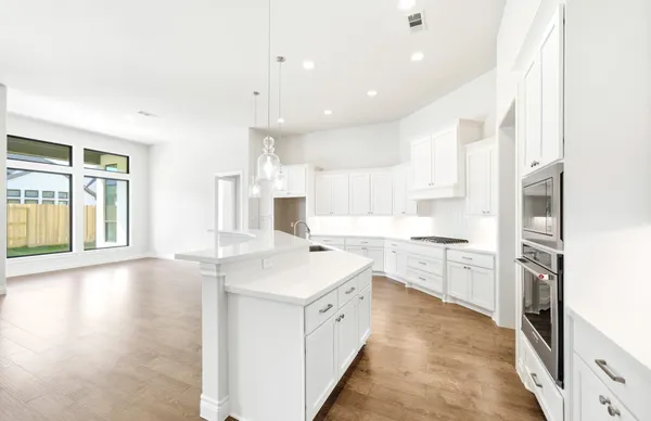 a large white kitchen with a large window a sink and white stainless steel appliances