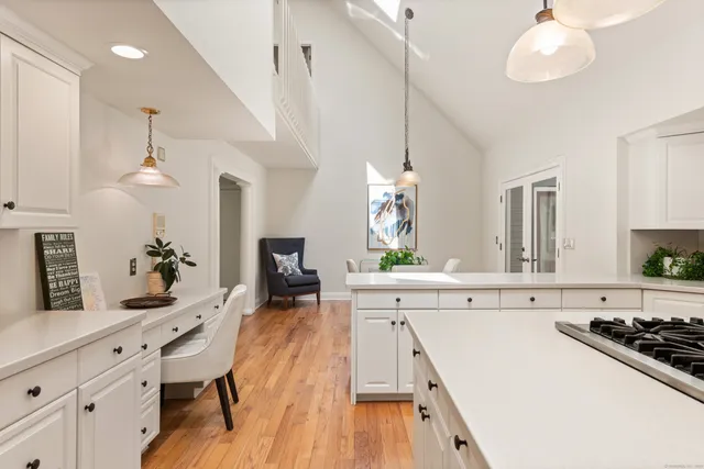 a large kitchen with stainless steel appliances a stove a sink dishwasher a dining table and chairs with wooden floor