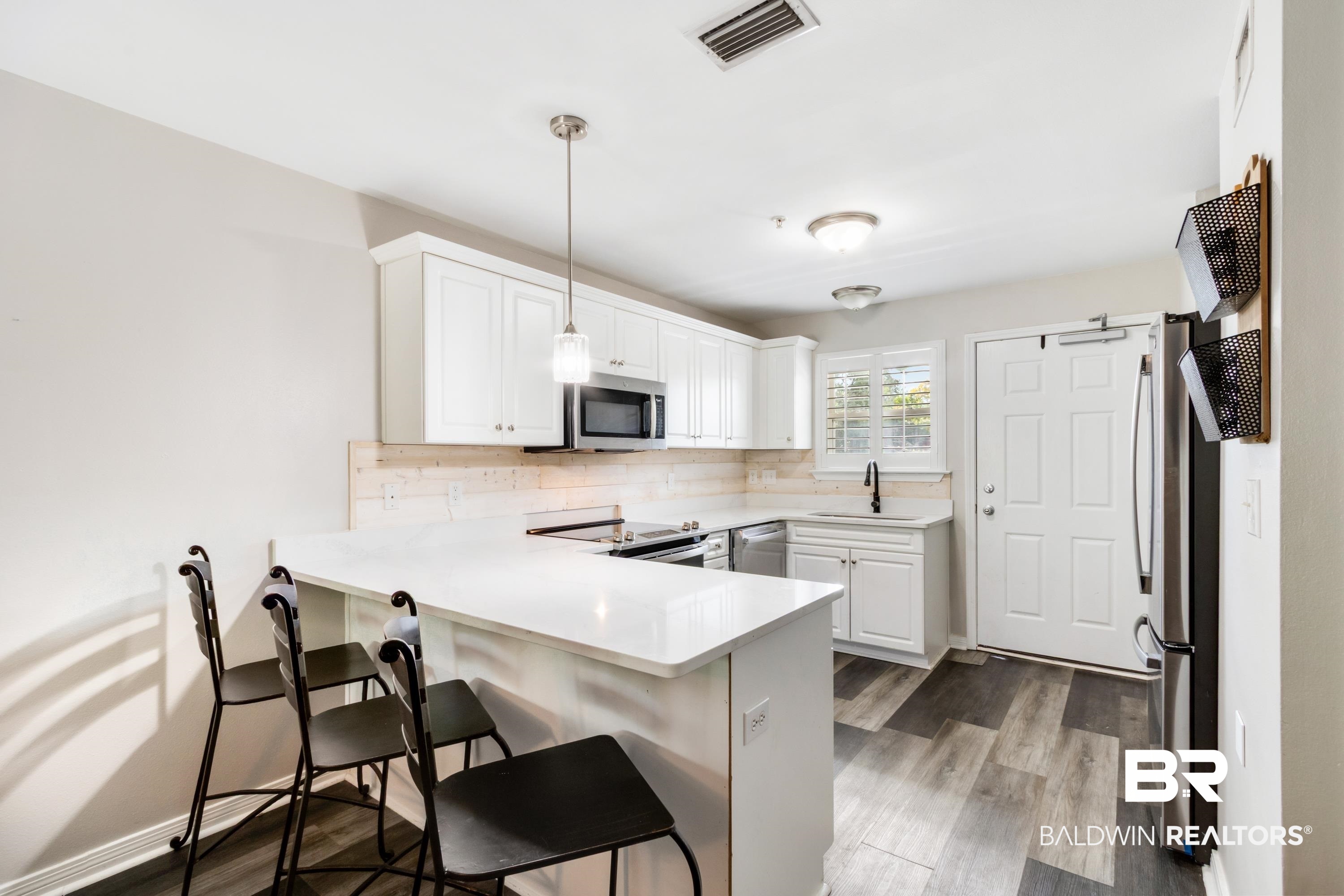 25957 Canal Road, Unit 208 Orange Beach, AL 36561 - Photo 7 of 28 Modern kitchen featuring white shaker cabinetry, stainless steel appliances, a white countertop, and wood-finish flooring