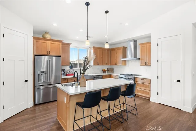 a kitchen with stainless steel appliances granite countertop a refrigerator a sink dishwasher a stove and white cabinets with wooden floor