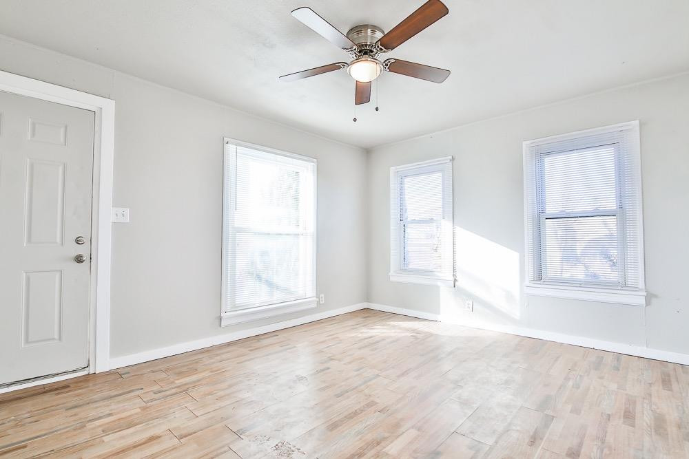 5705 County Road 1200 Lubbock, TX 79407 - Photo 13 of 29 an empty room with wooden floor ceiling fan and windows