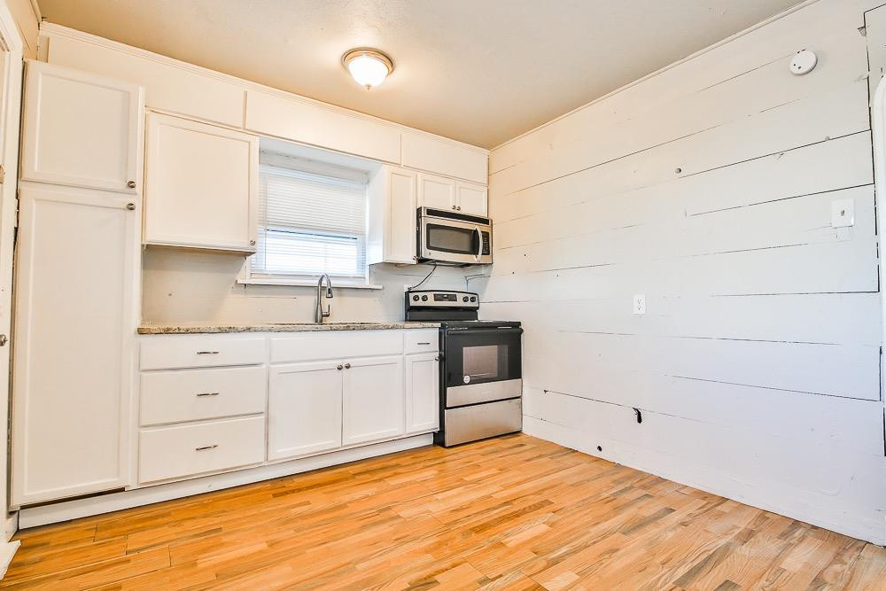 5705 County Road 1200 Lubbock, TX 79407 - Photo 24 of 29 a kitchen with granite countertop white cabinets and stainless steel appliances
