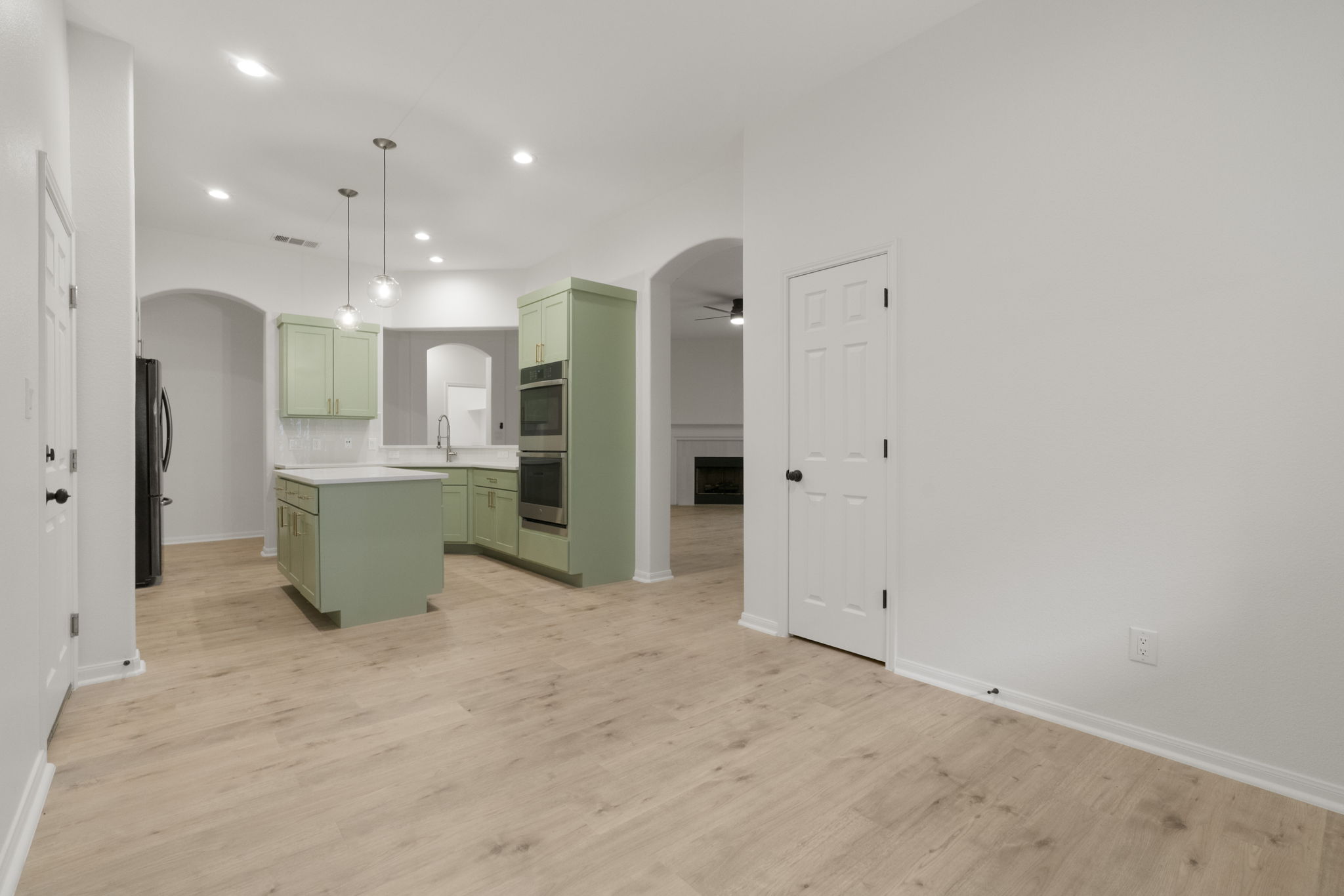 1333 Clary Sage Loop Round Rock, TX 78665 - Photo 11 of 34 Kitchen featuring green cabinets, arched walkways, light countertops, a fireplace, and recessed lighting