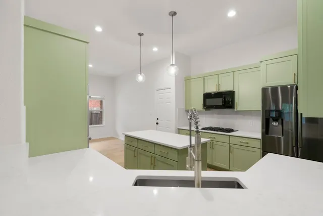 a kitchen with stainless steel appliances kitchen island a refrigerator sink and stove