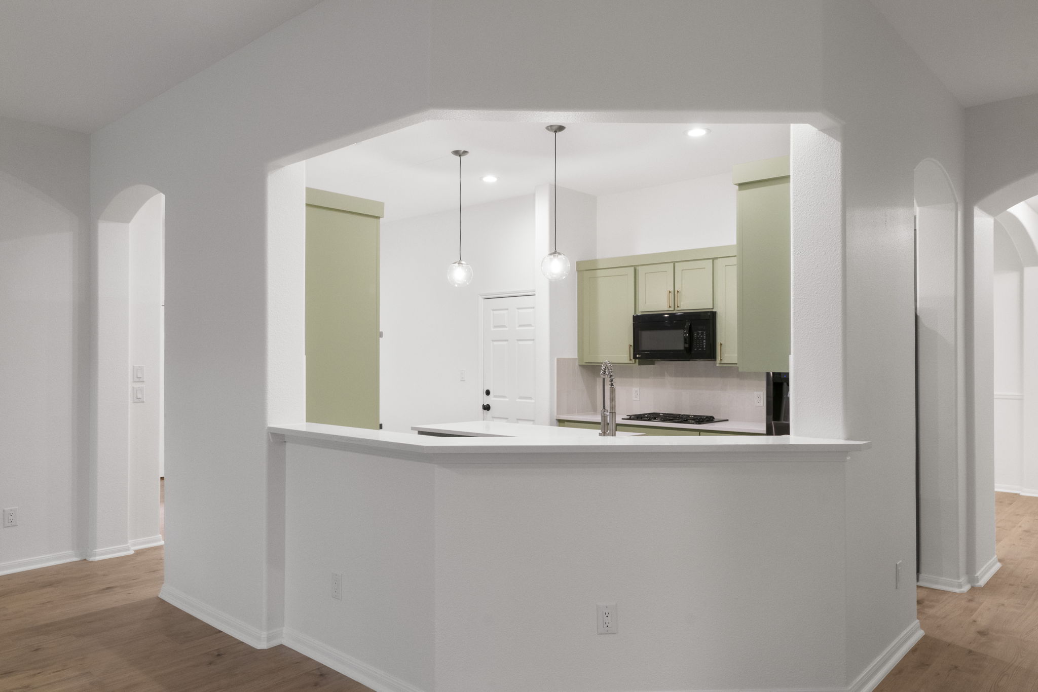 1333 Clary Sage Loop Round Rock, TX 78665 - Photo 6 of 34 Kitchen featuring arched walkways, light wood finished floors, decorative light fixtures, black microwave, and green cabinets